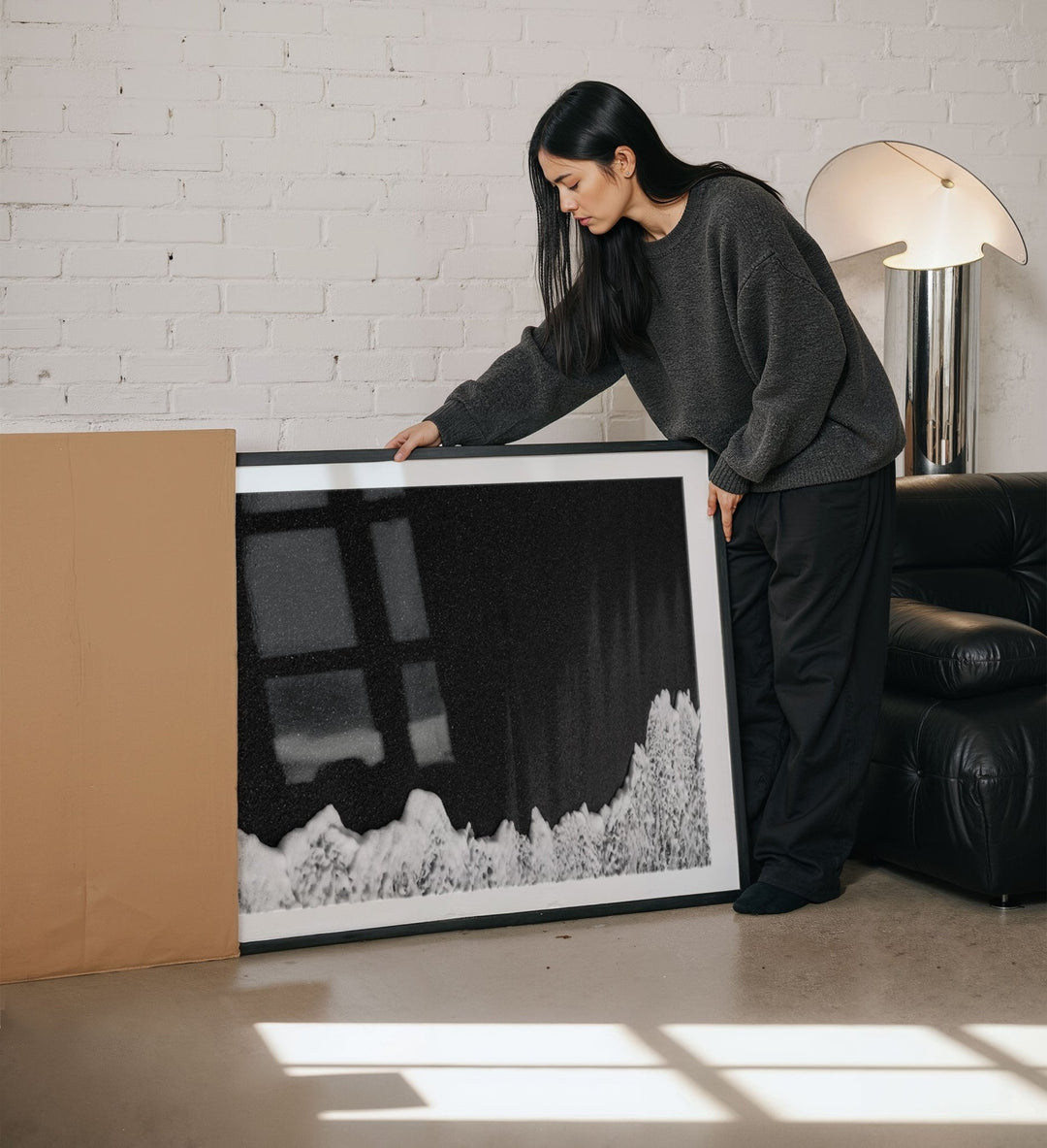 Woman holding a large artwork in a living room.