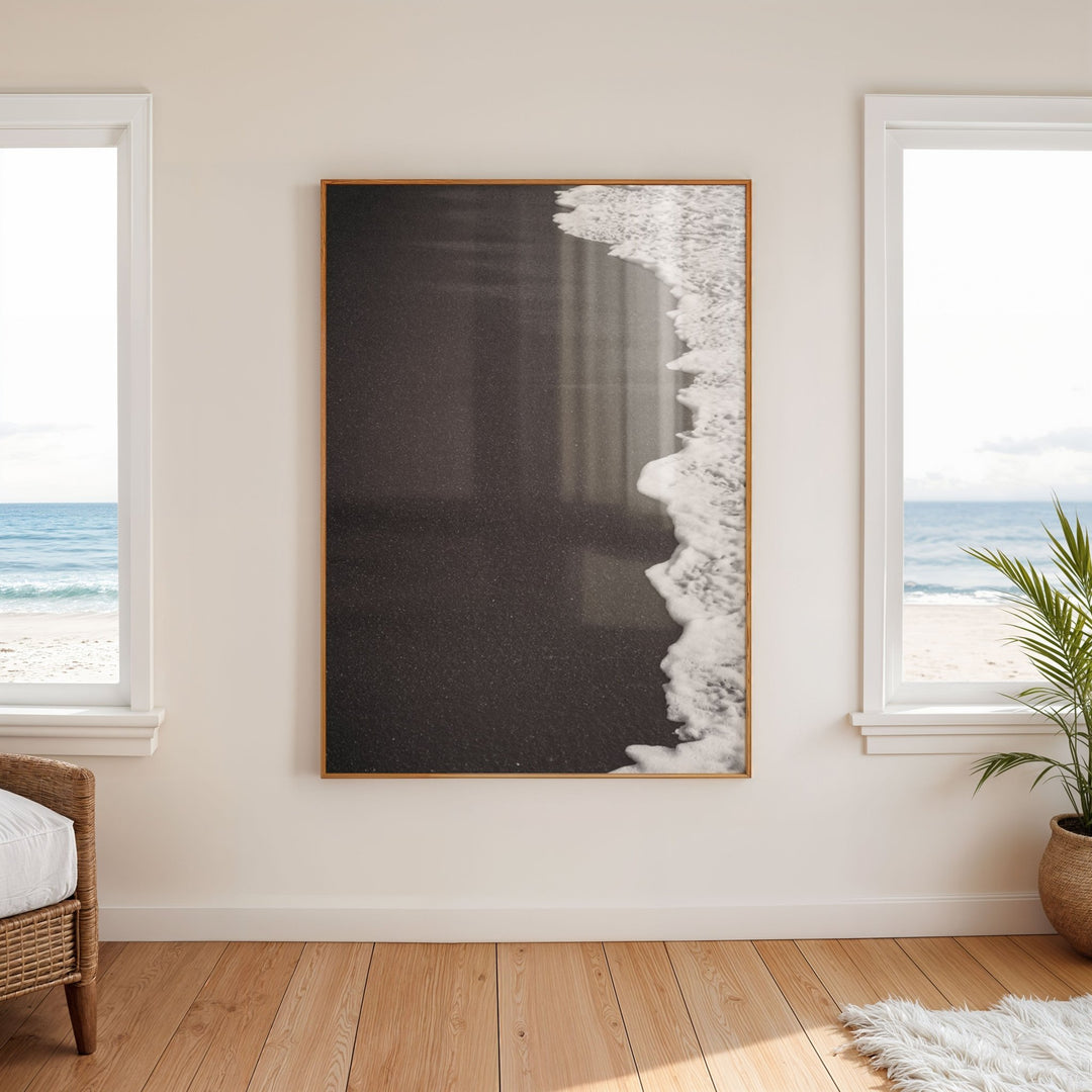 Abstract artwork on a wall with windows showing a beach view.