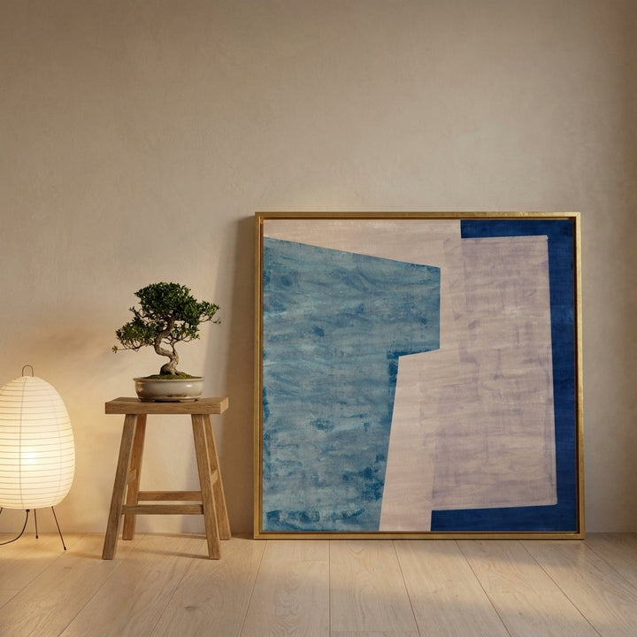 Canvas wall art with a gold leaf surround leaning against the wall in a warm Japandi living room