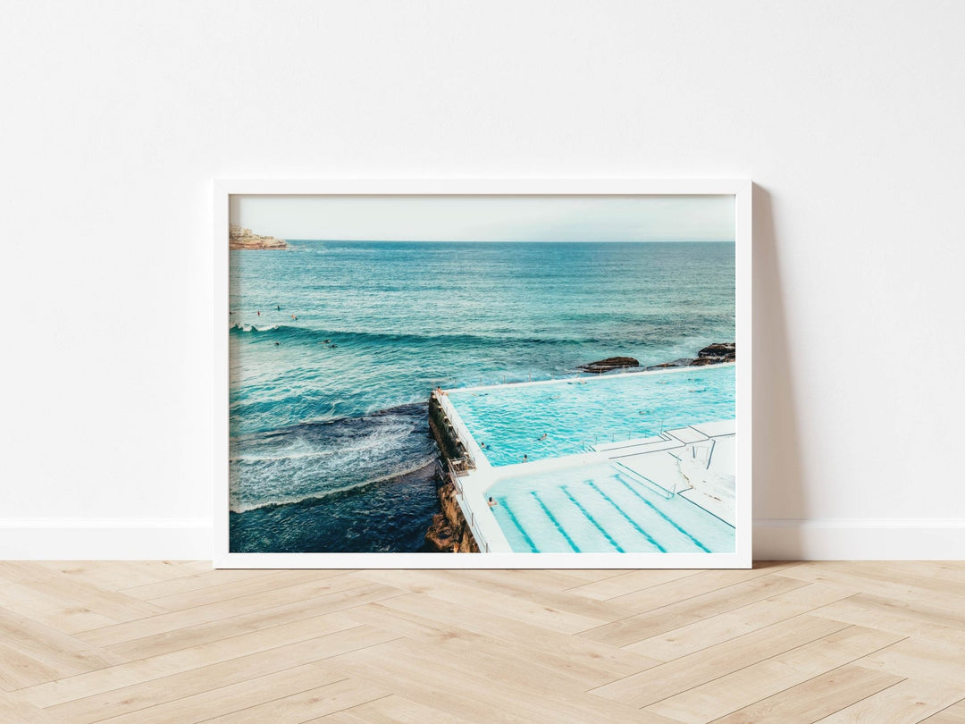 photograph of a pool with ocean view on a wooden floor.