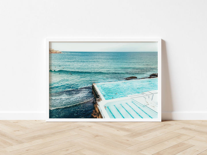 photograph of a pool with ocean view on a wooden floor.