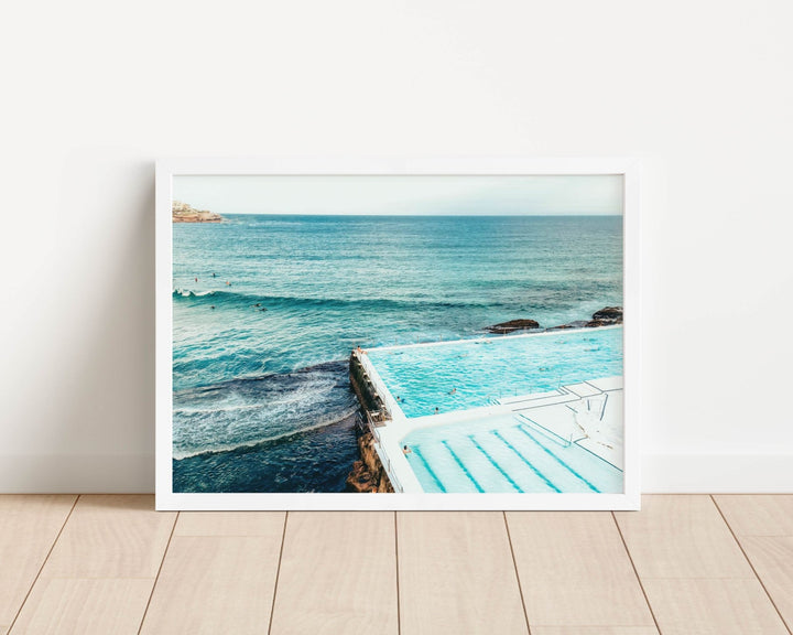 photograph of a pool with ocean view on a wooden floor.