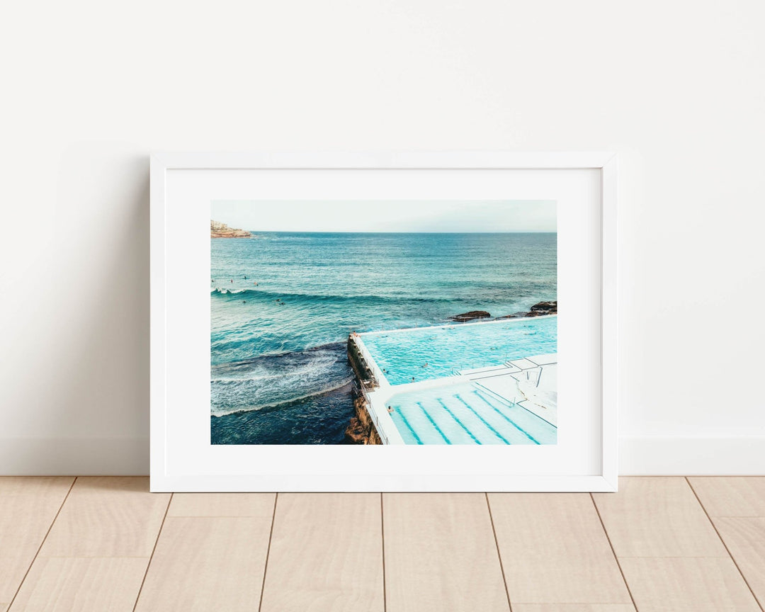  photograph of a pool with ocean view on a wooden floor.