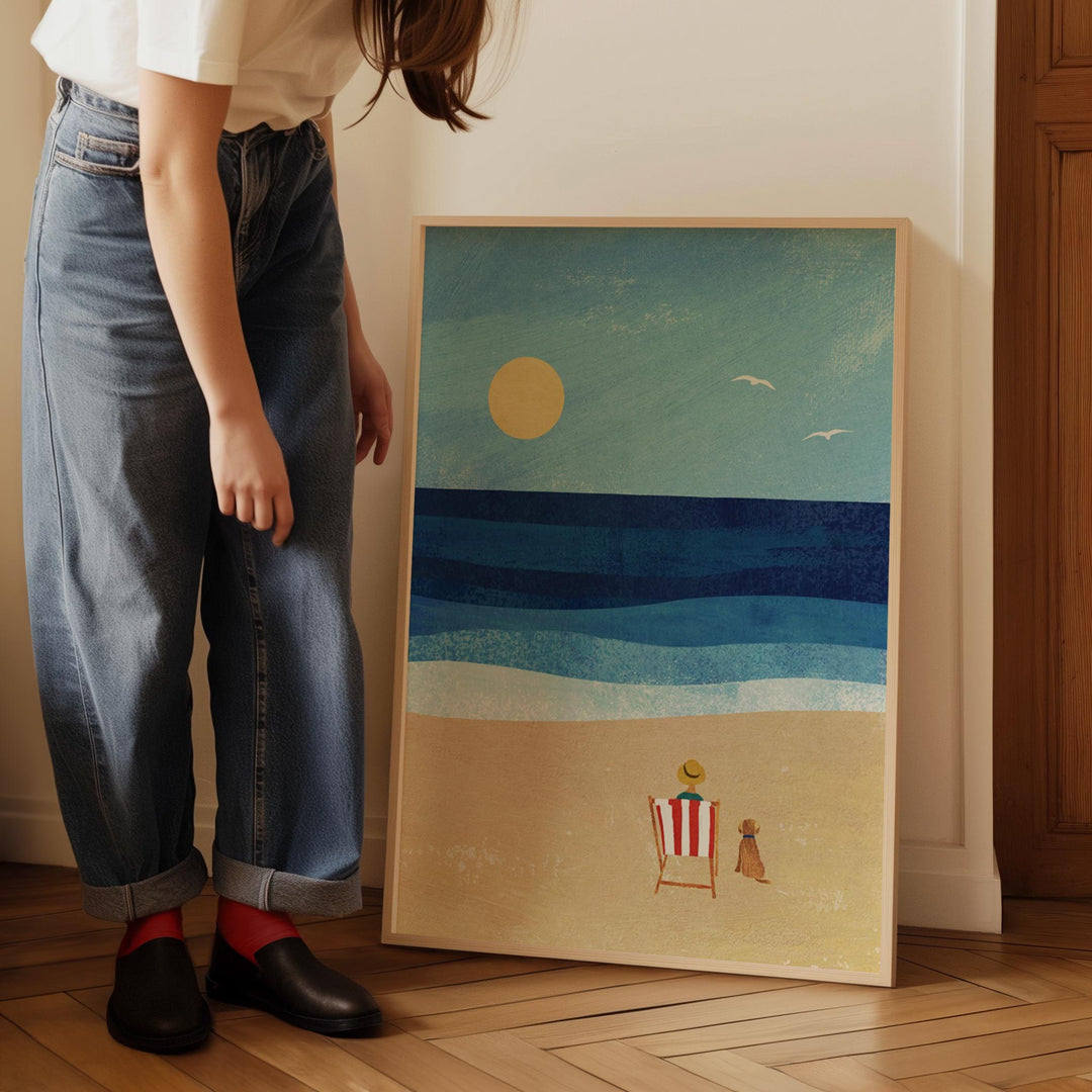 Person standing next to artwork of a beach scene with a sunset.