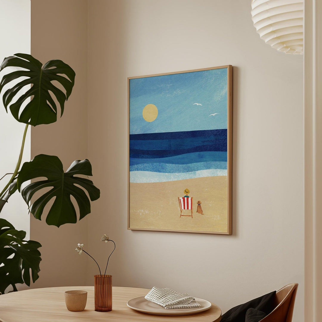 Artwork of a beach scene on a wall with a plant and table in the foreground.