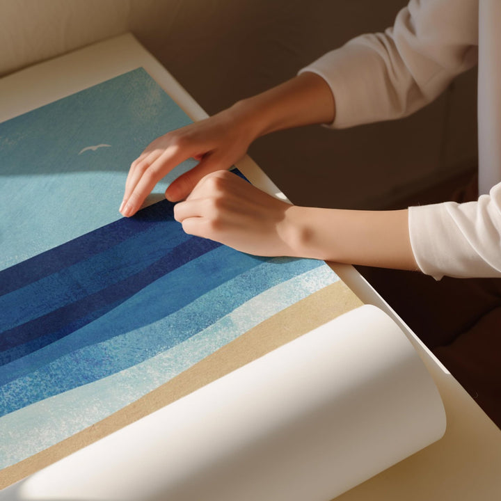 Person unrolling a blue and white striped fabric on a table.