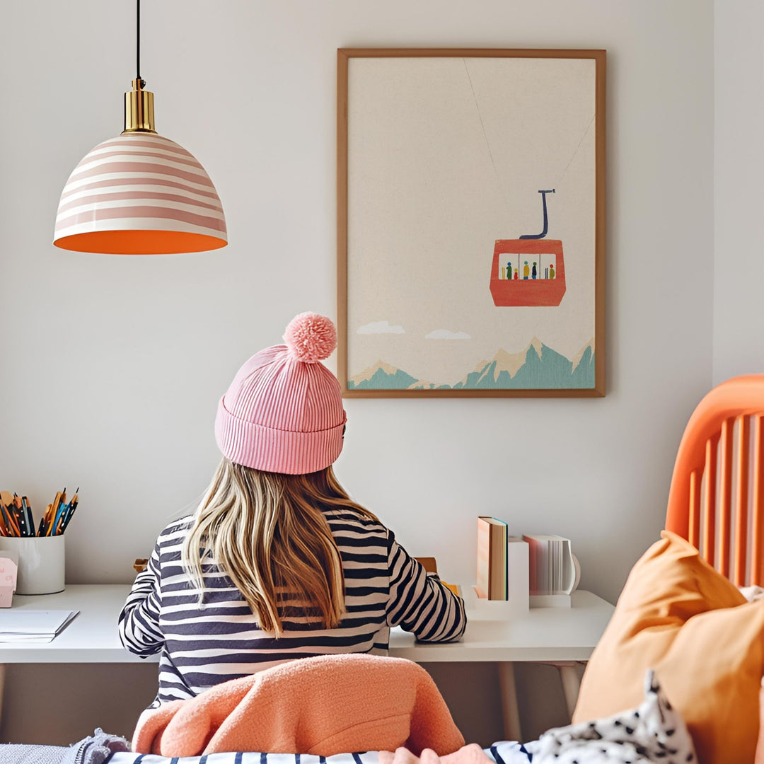 Person wearing a pink beanie sitting at a desk with  picture on the wall.