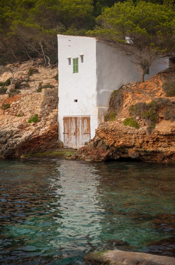 White building embedded in rocky cliffs by the sea framed