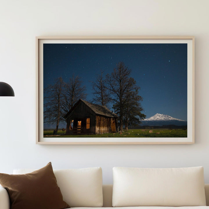 Living room with a picture of a cabin and mountain, white sofa, and decorative items.