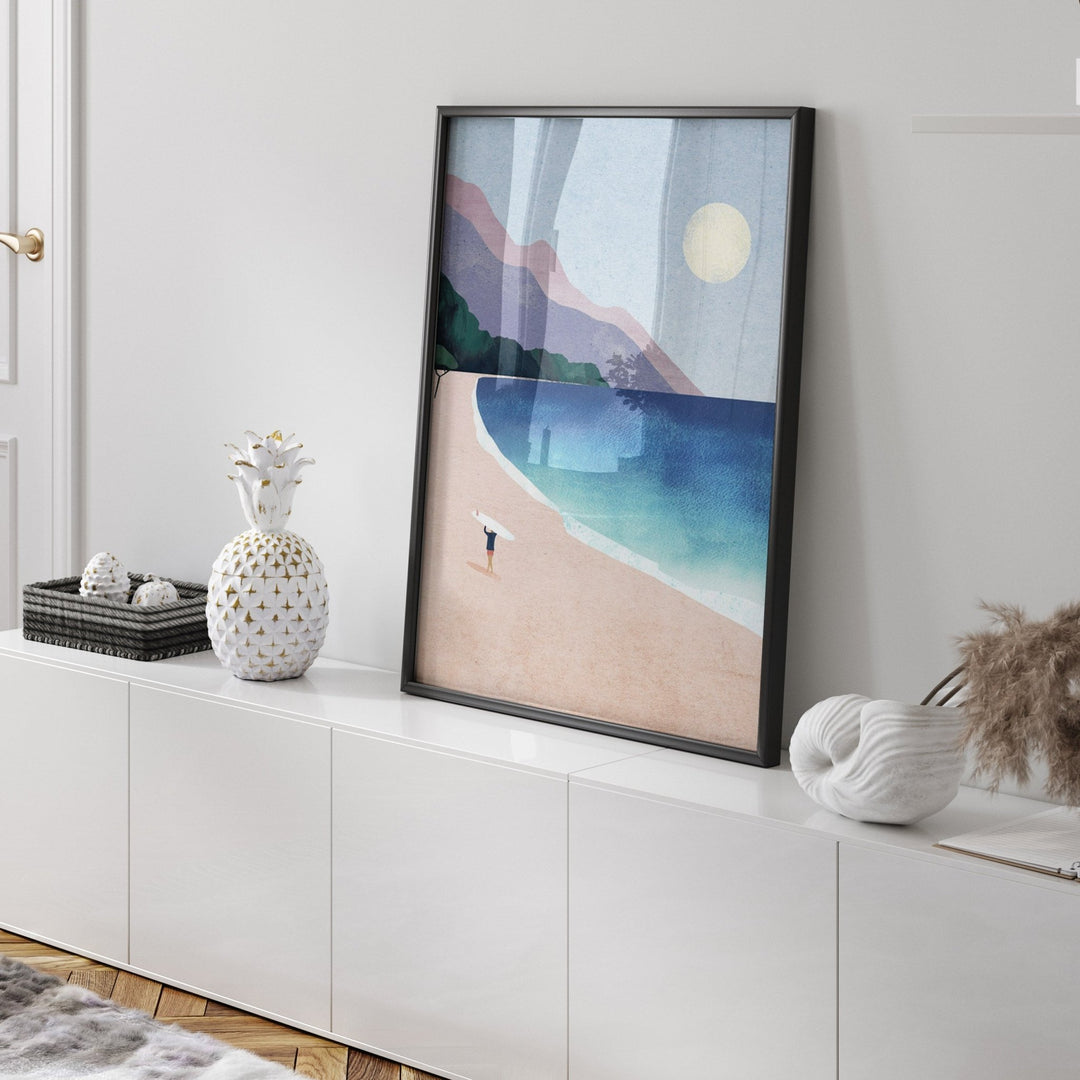 Beach artwork on a white wall above a white cabinet.