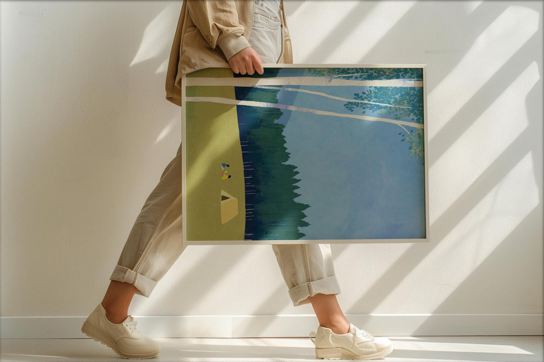 Person holding an artwork with a natural scene in a minimalistic setting