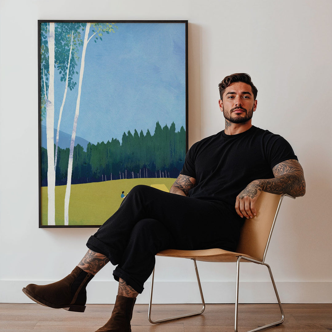 Man sitting on a chair in a room with a large painting of a forest scene.