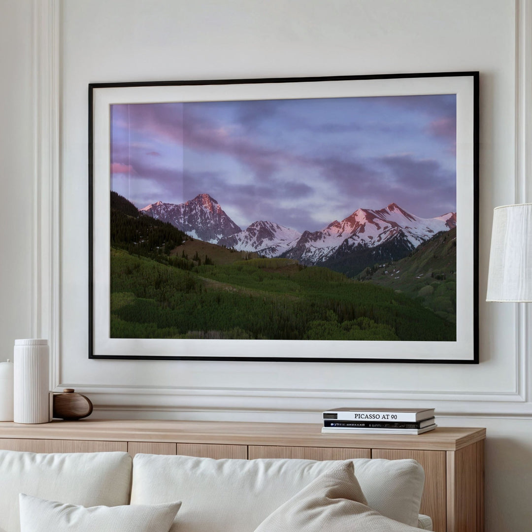 Living room with a white sofa, wooden coffee table, and mountain landscape on the wall.
