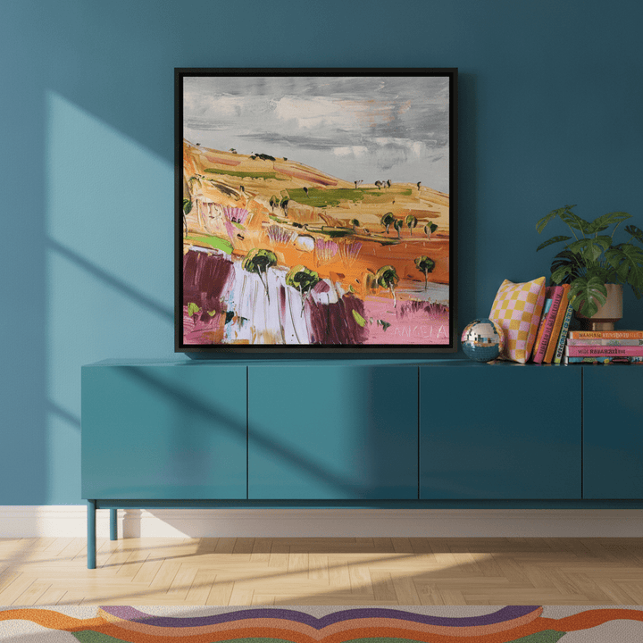 Canvas wall art with a black surround standing on a sideboard in a colourful eclectic home office