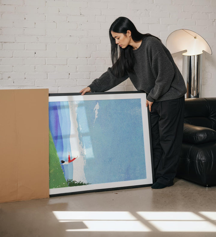 Woman holding a large picture in a living room.