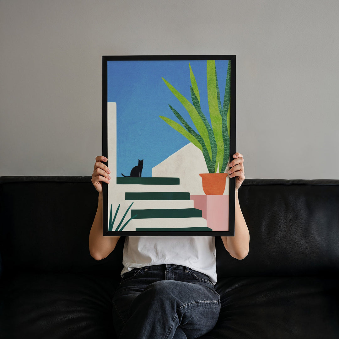 Person holding an artwork of a cat and plant on a wall.