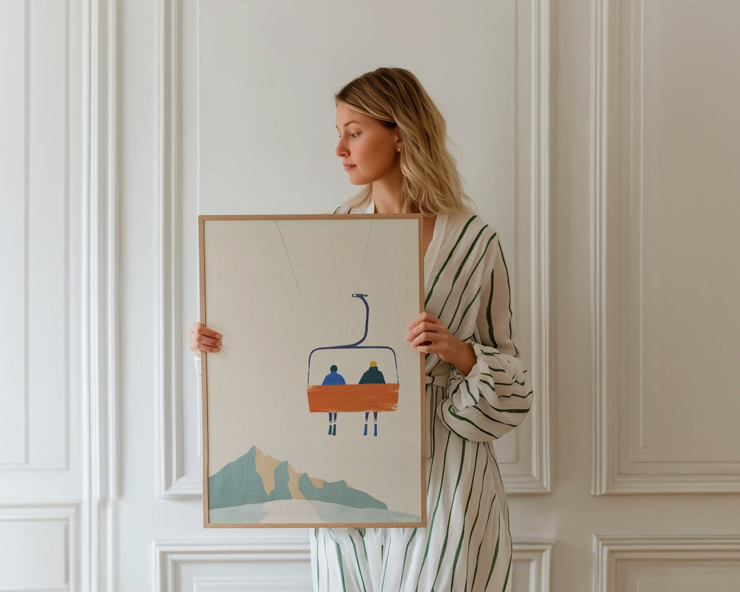 Woman holding an artwork of a mountain landscape with a chairlift.