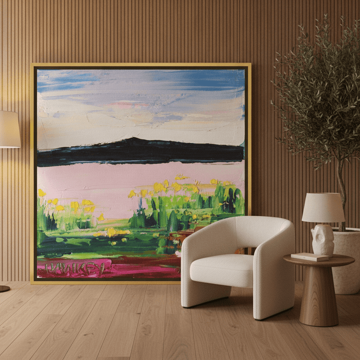 Oversized statement canvas wall art with a gold leaf surround leaning against the wall in a luxe living room
