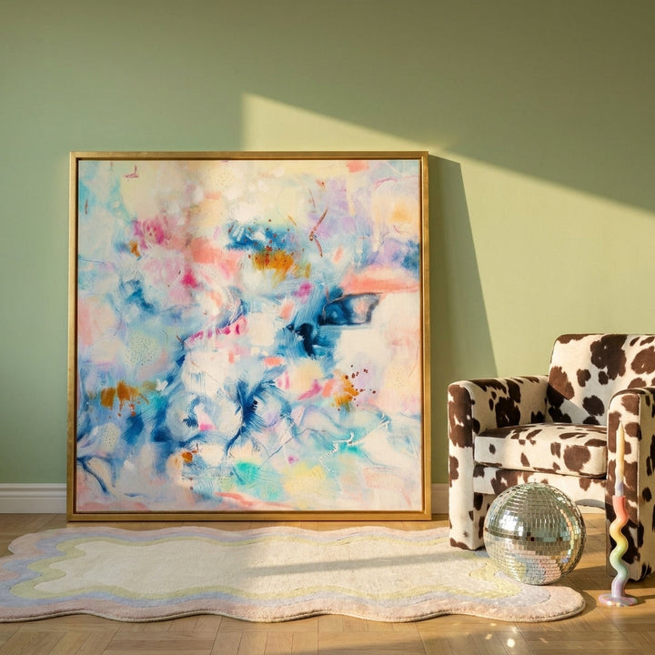 Canvas wall art with a gold leaf surround leaning against the wall in a colourful eclectic living room