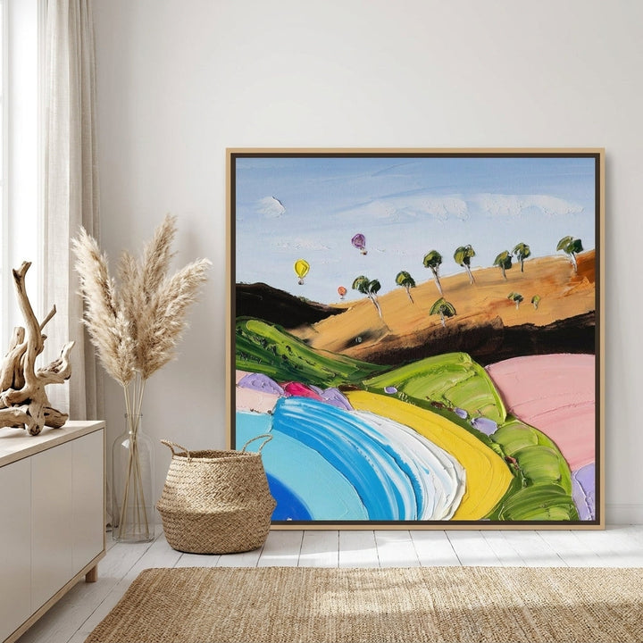 Oversized statement canvas wall art with a natural timber surround leaning against the wall in a coastal dining room