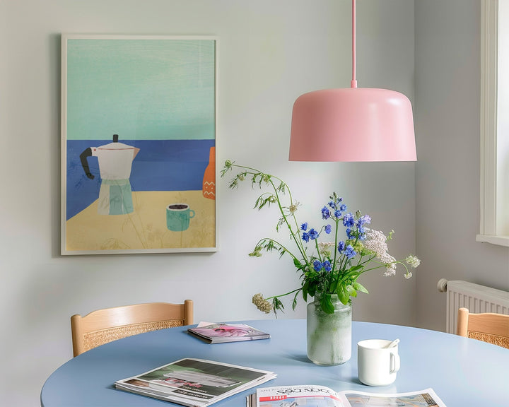 pink lamp over a blue dining table with artwork hanging on wall