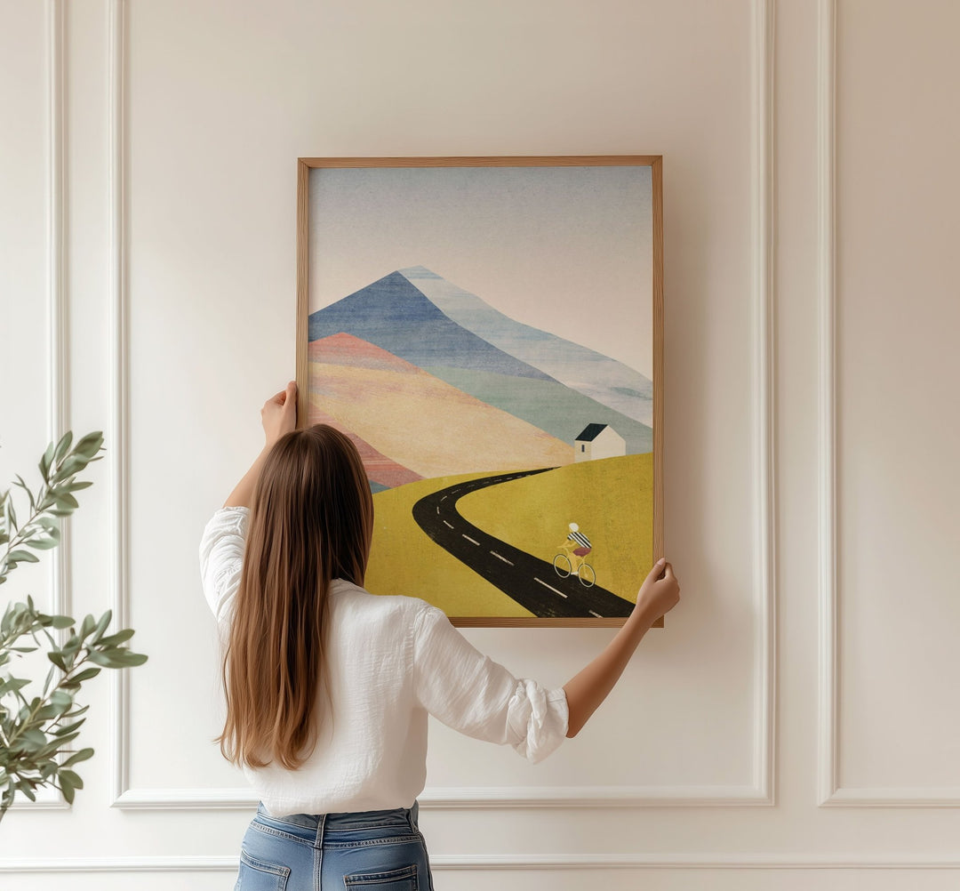 Person hanging a landscape painting on a wall