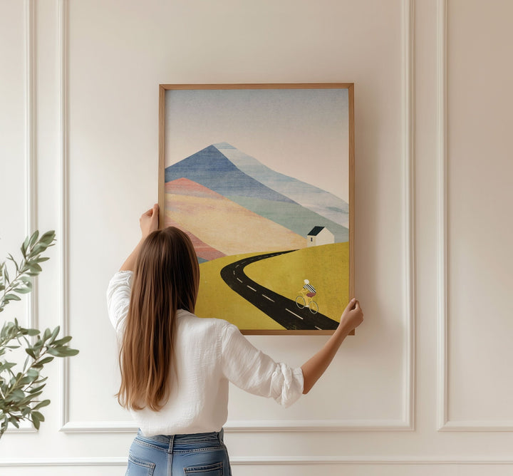Person hanging a landscape painting on a wall