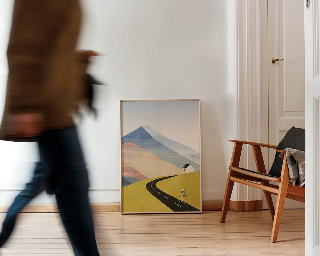 Person walking past a wall with an abstract landscape painting in a room with wooden flooring.