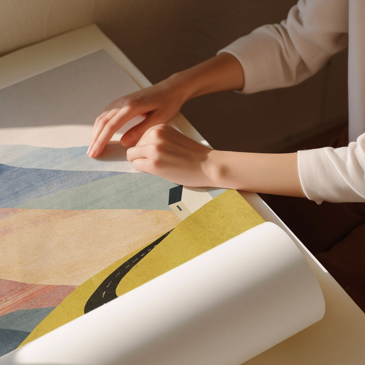 Person unrolling a colorful abstract painting on a table.