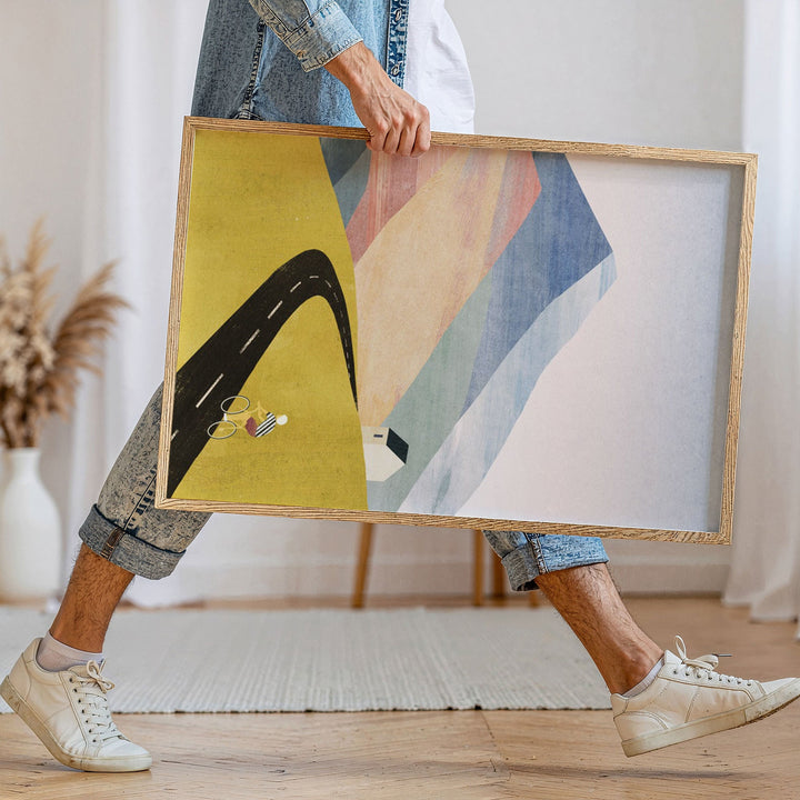 Person holding two abstract artworks in a room with a neutral decor.