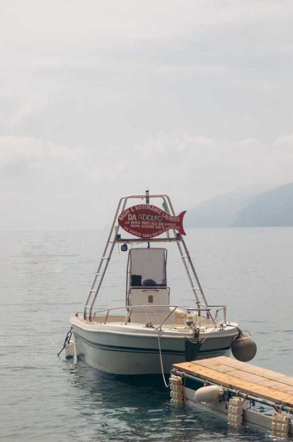 Boat with a 'Da Rogers' sign on a dock by a calm body of water framed