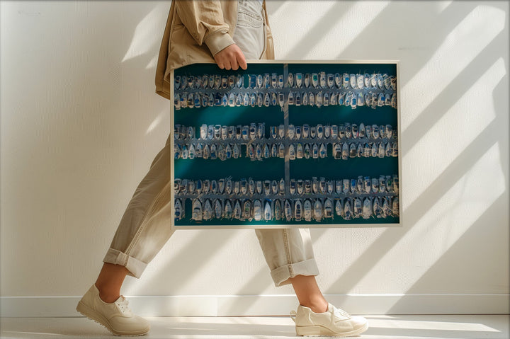 Person holding a large photo album filled with photos against a white wall.