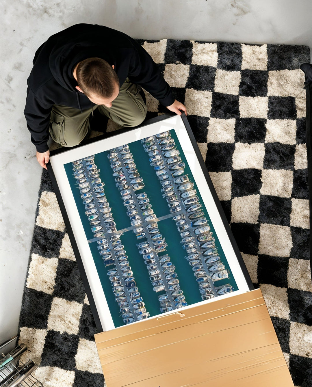 Person holding a large artwork on a checkered rug