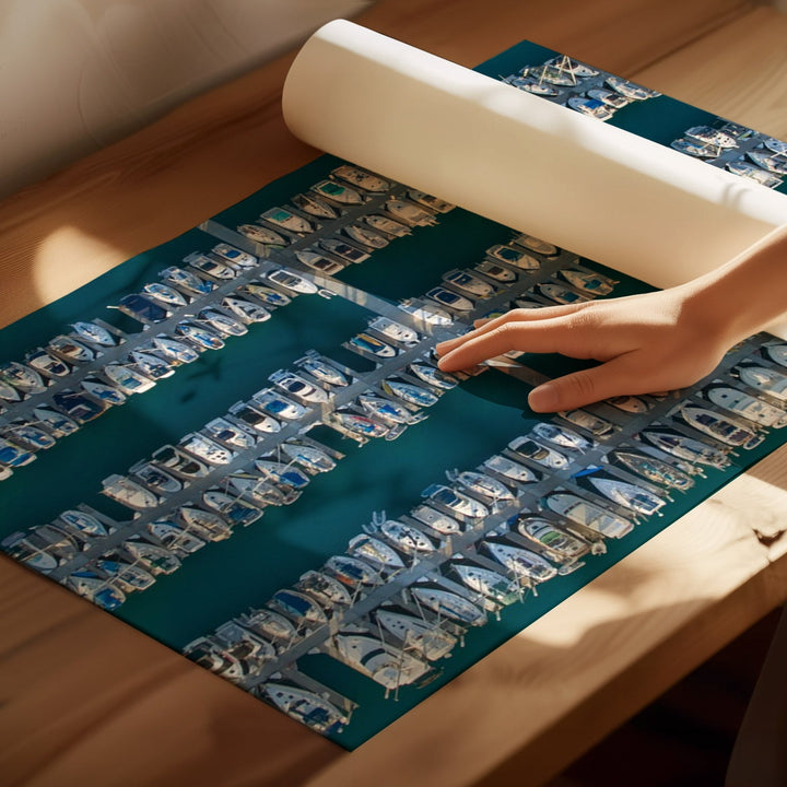Person rolling up a mat with boat images on a wooden surface