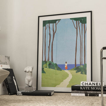 Artwork of a scenic landscape on a coffee table with books and a lamp in a room.