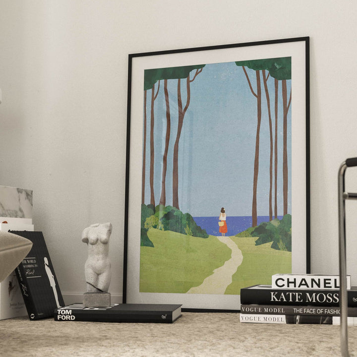 Artwork of a scenic landscape on a coffee table with books and a lamp in a room.