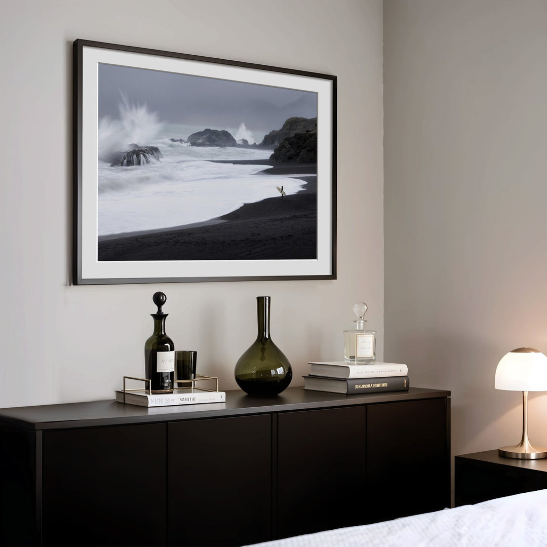 black and white beach scene above a dark wooden console table with decorative items.
