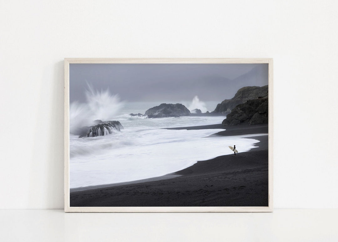 Black and white landscape print of a snowy mountain scene with a person standing on a beach.