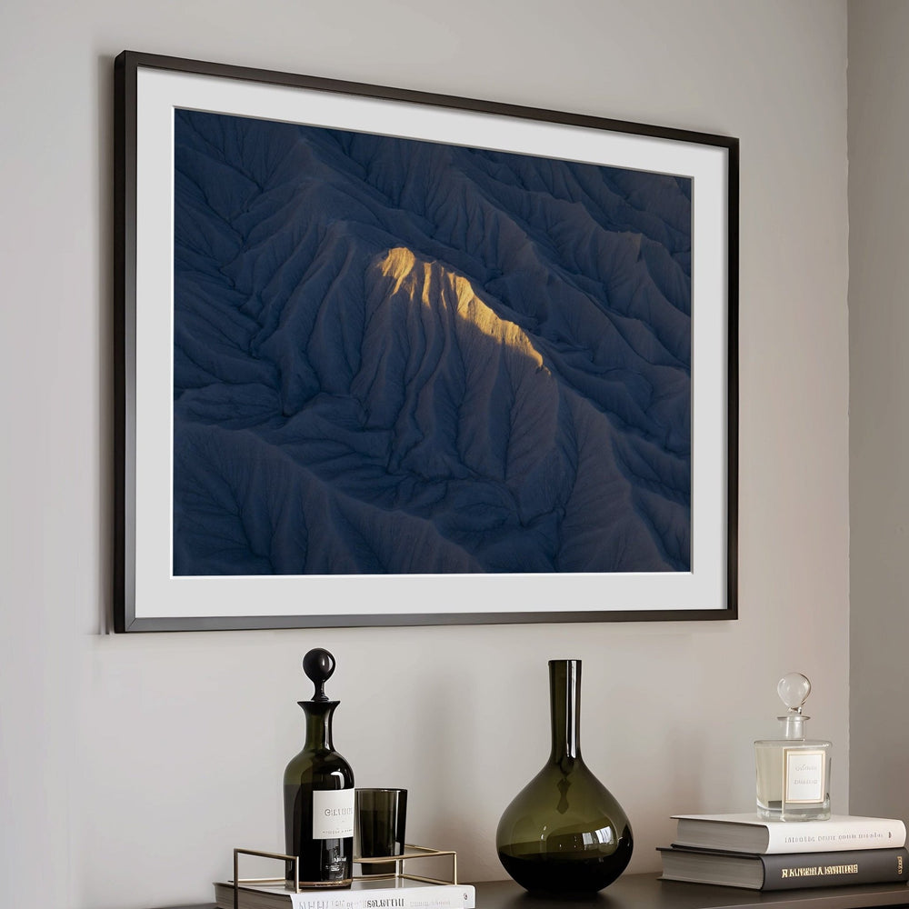 Artwork on a wall above a dark wooden cabinet with decorative items.