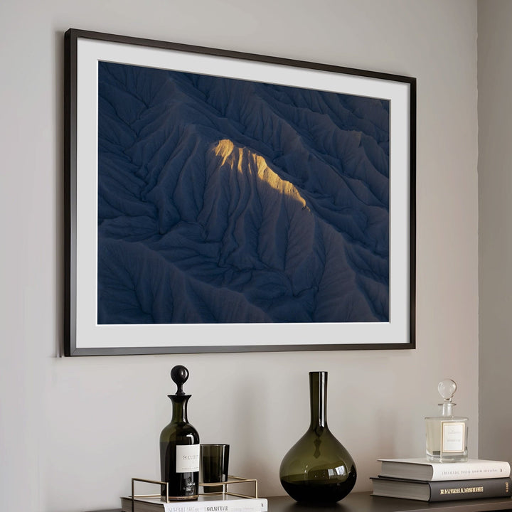 Artwork on a wall above a dark wooden cabinet with decorative items.