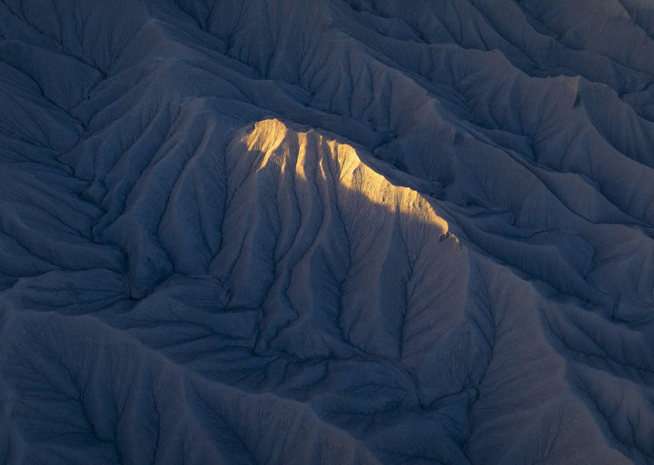 Sunlight illuminates a mountain peak in a desert landscape. framed