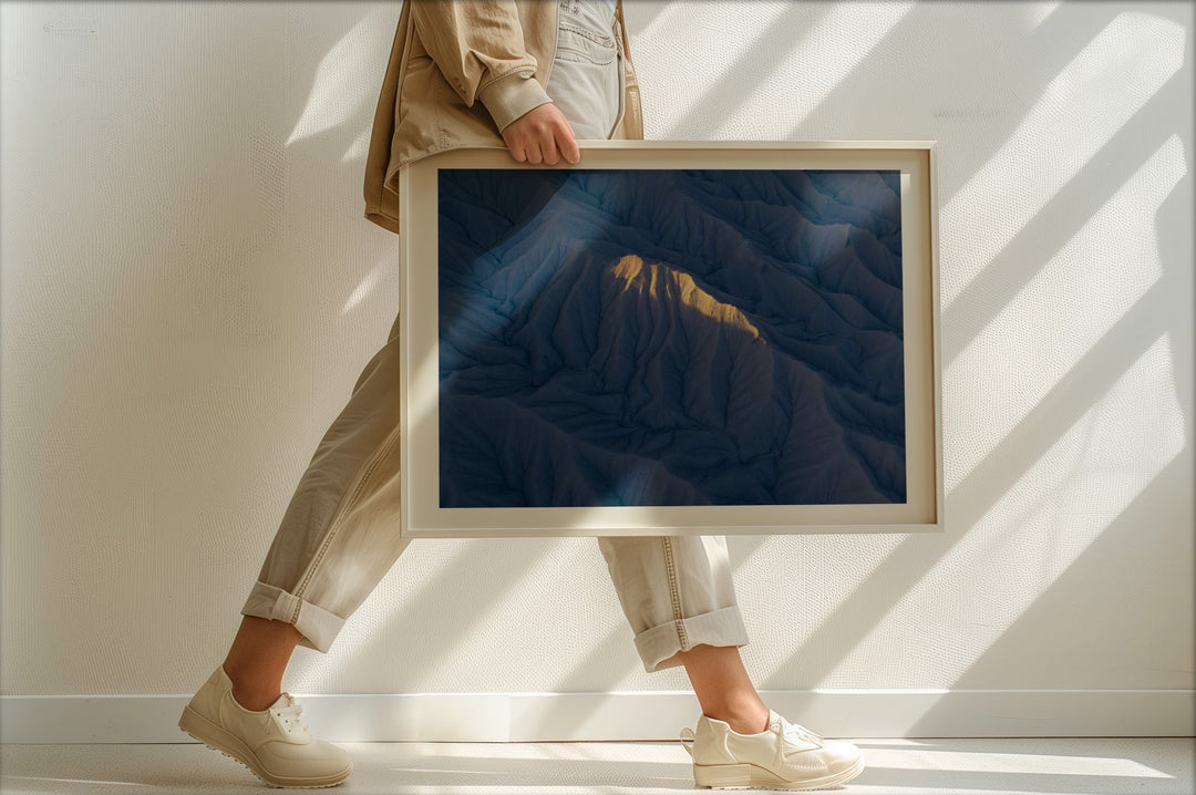 Person holding a picture of a mountain against a white wall