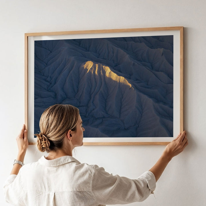 Person hanging artwork of mountains on a wall