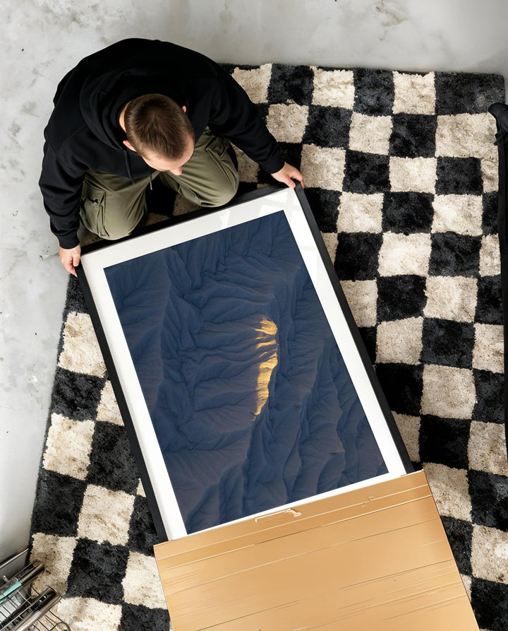 Person handling a large photo on a checkered rug