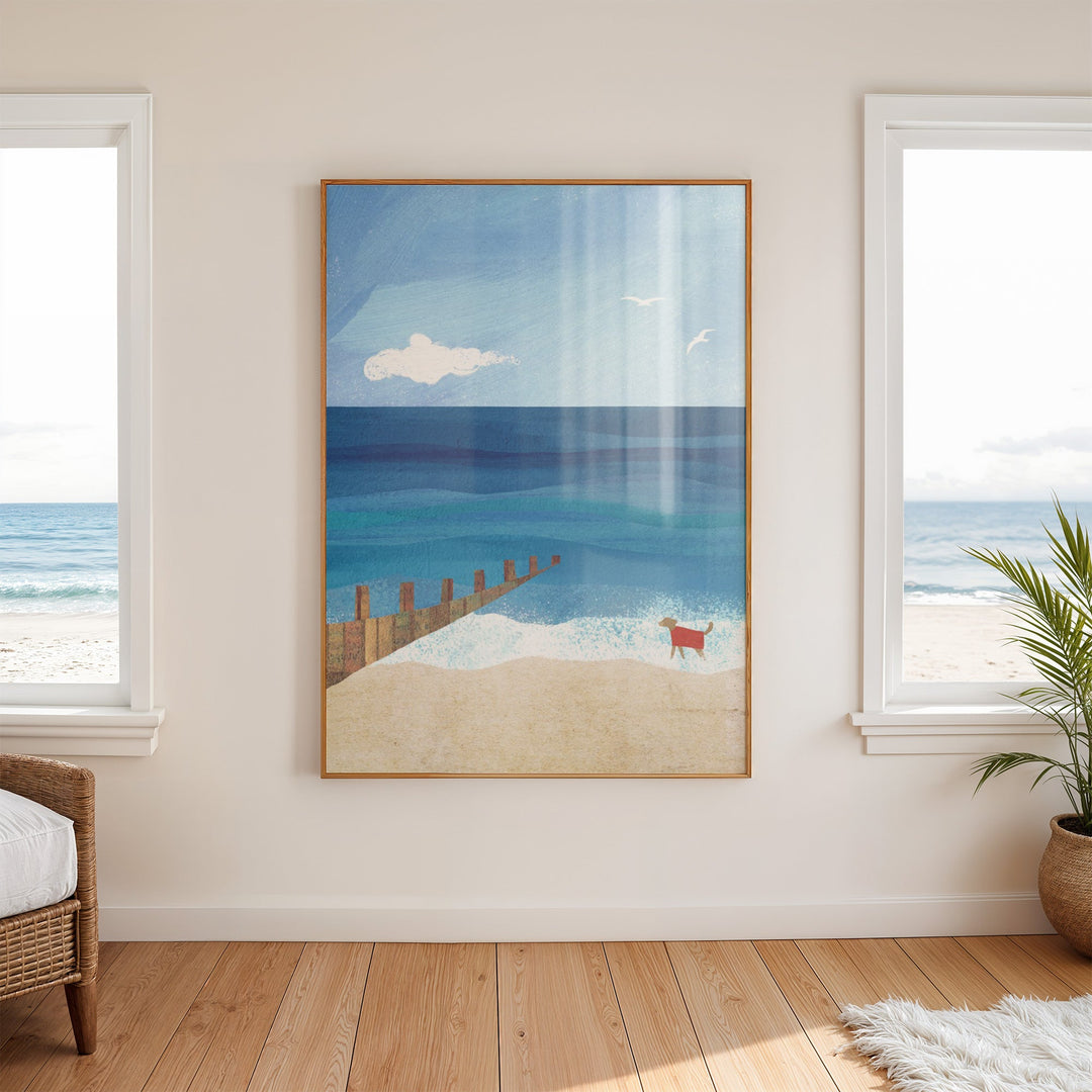 Artwork of a beach scene with a dog on a wall in a room with large windows.