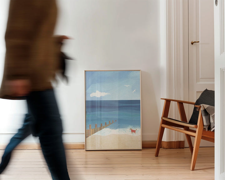 Room interior with an artwork of a beach scene and a wooden chair.