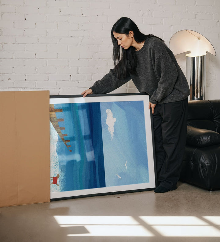 Woman holding an artwork in a living room.