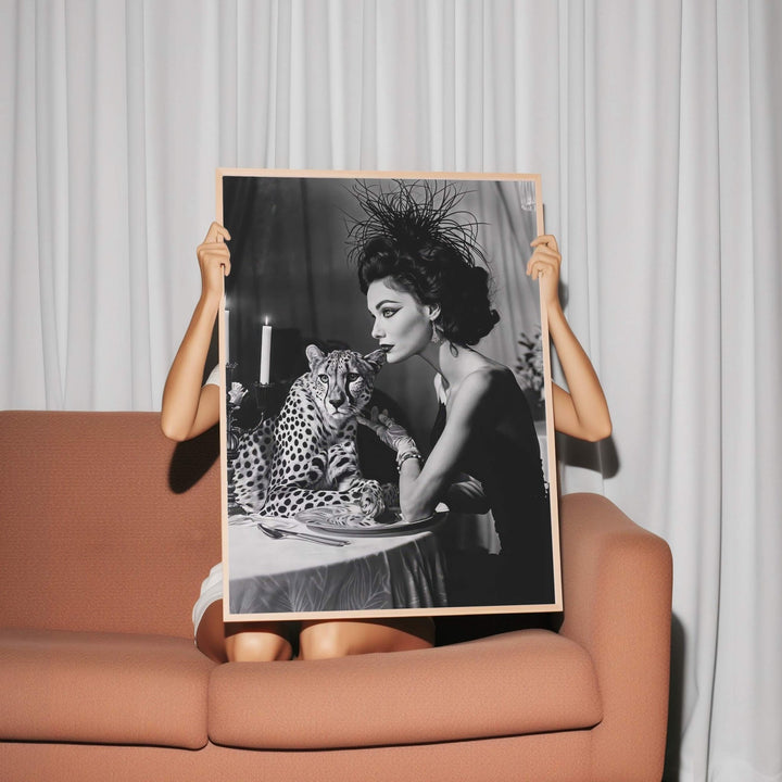 Person holding a black and white photograph of a woman with a leopard on a couch.