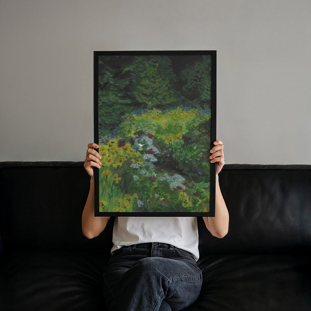 Person holding a painting of a garden scene in front of their face on a dark couch.