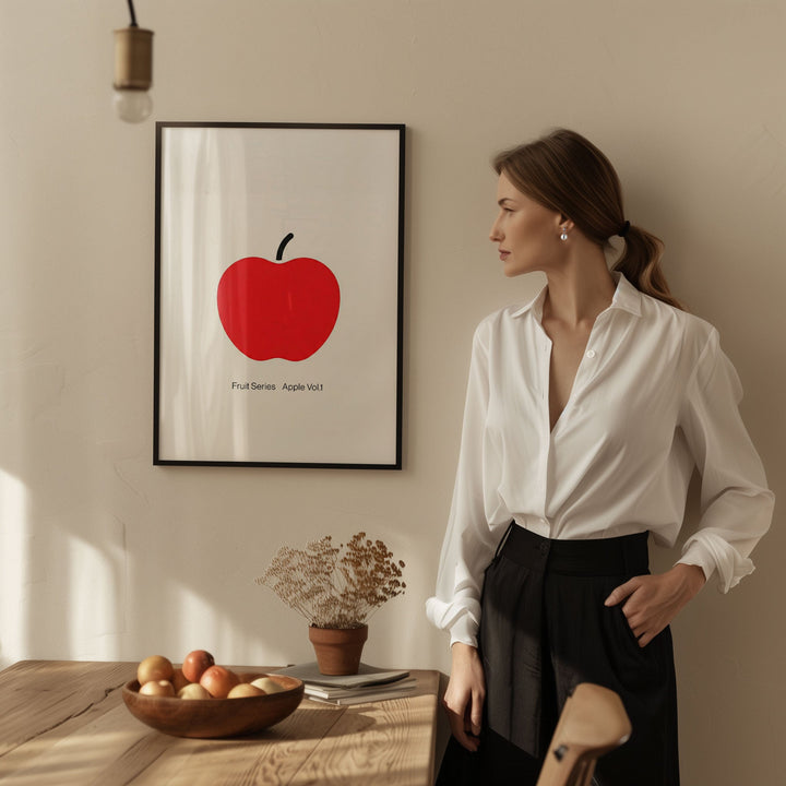 Woman standing in a room with a picture of a red apple on the wall.